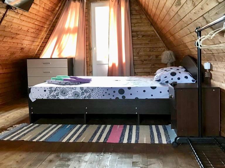 Спальня под деревянной скатной крышей с двуспальной кроватью